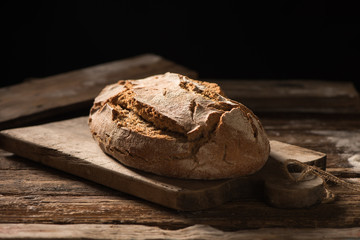 Freshly baked bread on wooden table on dark background