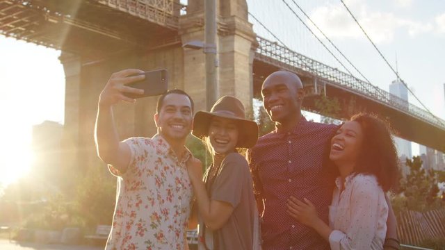 Group Of Friends Posing For Selfie In Front Of Brooklyn Bridge