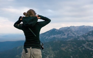 Young woman photographer preparing for a storm at the top of the mountain