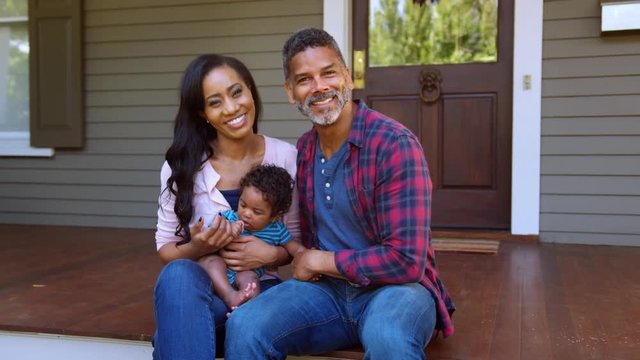 Portrait Of Parents With Baby Son Sitting On Steps Of House
