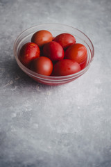 Set of six colored red inside a glass bowl for Easter holidays, coloring with red tint eggs over a gray concrete background