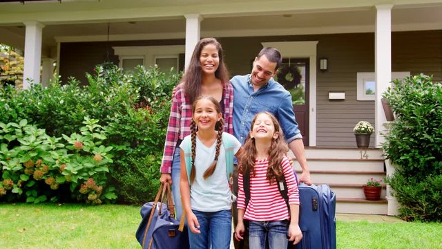 Portrait Of Family With Luggage Leaving House For Vacation