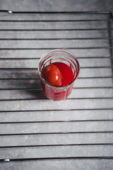 Red colored eggs with red tint are displayed on a metallic grate  top view over a gray concrete...