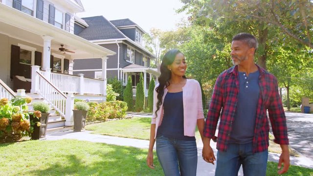 Couple Walking Along Suburban Street Holding Hands