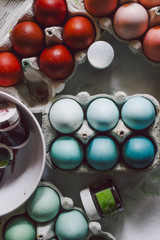 Packages with Dyed eggs for Easter holidays, colored  with red,blue,green and pink tint inside package are set over a gray concrete background
