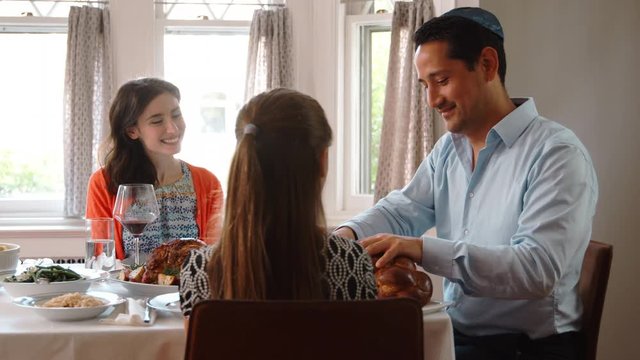 Jewish man sharing challah with family at Shabbat, close up