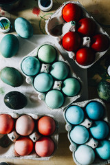 Packages with Dyed eggs for Easter holidays, colored  with red,blue,green and pink tint inside package are set over a gray concrete background