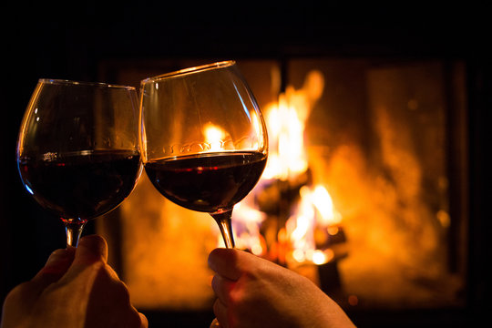 Couple holding pair of glasses with wine at fire pit