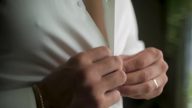 Close up of businessman wears a white shirt. Clip. Close up of man dressing up and adjusting white shirt with cufflinks. The man in the white shirt in the window dress cufflinks.