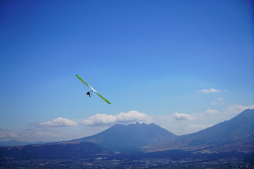 Fototapeta na wymiar 熊本県の阿蘇山　外輪山の大観峰に飛ぶカイトやパラグライダー