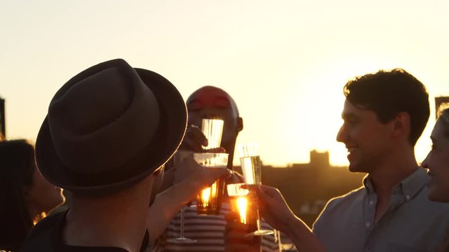 Friends making a toast on a rooftop at sundown, close up