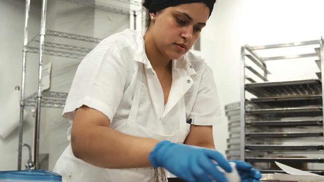 Hispanic woman cutting cookie dough at a bakery, close up