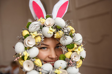 Portrait of young woman with bunny ears and spring wreath with easter eggs. Happy easter background