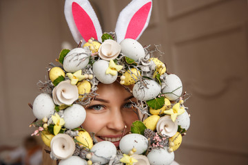 Obraz na płótnie Canvas Portrait of young woman with bunny ears and spring wreath with easter eggs. Happy easter background