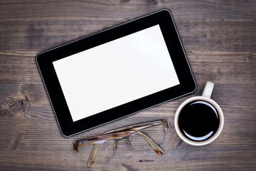 Black tablet pc on table with coffee cup and eyeglasses