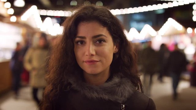 Portrait Of Smiling Woman Enjoying Christmas Market At Night