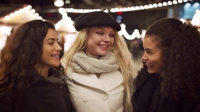 Portrait Of Female Friends Enjoying Christmas Market At Night