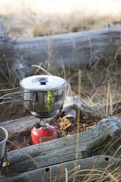 A simple camp cooking set-up with steam rising from the pot