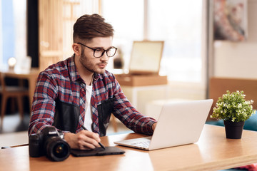 Freelancer man drawing at laptop sitting at desk.