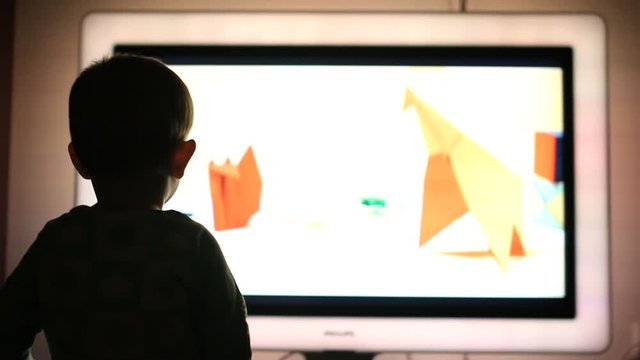 Media education, little baby boy silhouette watching on big TV screen cartoons 