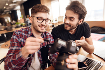 Two freelancer men taking out memory card at laptop at desk.