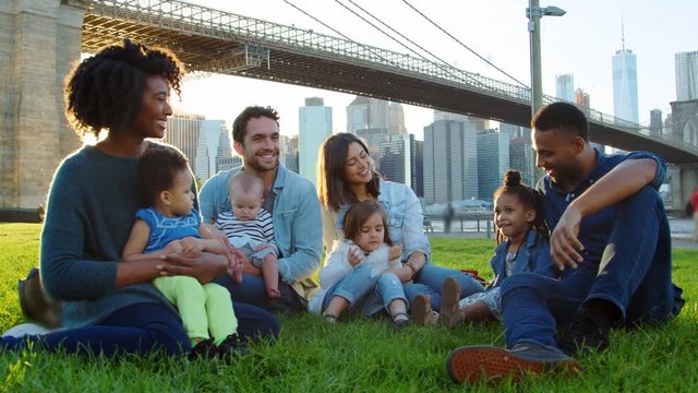 Two families with young kids sitting by bridge in Manhattan