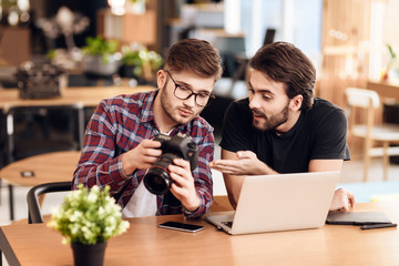 Two freelancer men looking at photos at laptop at desk.