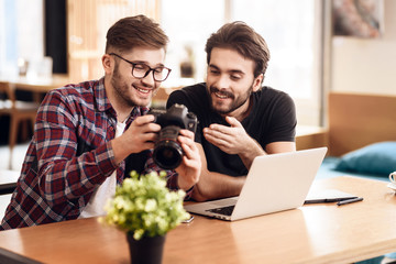 Two freelancer men looking at photos at laptop at desk.
