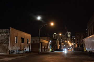 Fototapeta na wymiar Urban city street with vintage industrial warehouses and the Chicago skyline with the moon at night