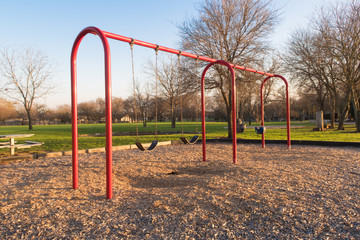 Fototapeta na wymiar swingset painted red with two types of seats