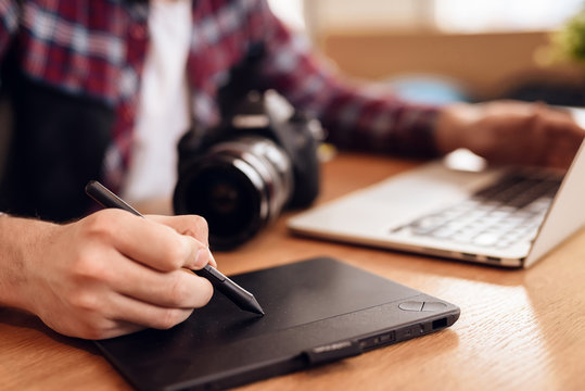 Close up freelancer man drawing on tablet at laptop sitting at desk.