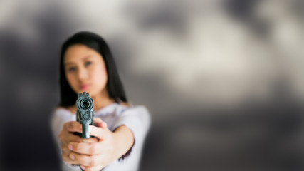 Young Asian female with handgun in hands point gun to target in front