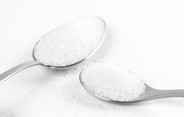 Sugar in a two spoons. Close up. Isolated on a white background