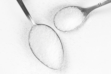 Sugar in a two spoons. Close up. Isolated on a white background