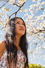 Naklejka premium Asian girl with blooming tree and white flowers
