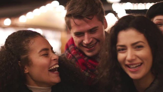Portrait Of Young Friends Enjoying Christmas Market At Night