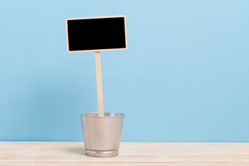 a blank blackboard label with iron bucket isolated on a blue background