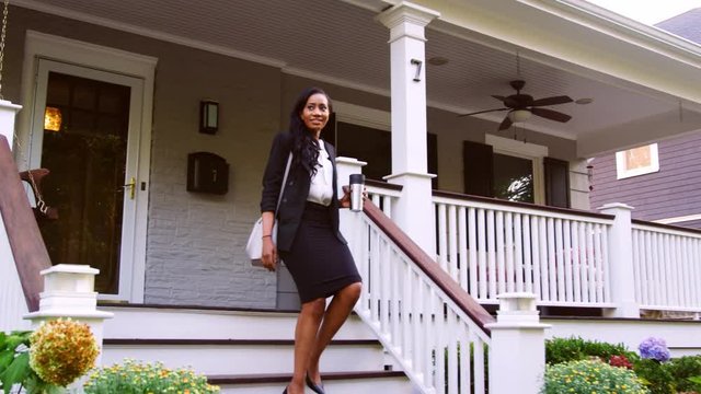 Businesswoman With Cup Of Coffee Leaving Suburban House For Work