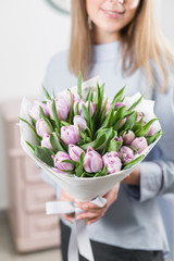 Sunny spring morning. Young happy woman holding a beautiful bunch of lilac tulips in her hands. Present for a smiles girl. Flowers bouquet in headbox