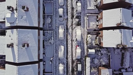 Aerial flight down a traditional UK terraced house street that’s covered in snow after a blizzard the night before. Filmed at sunrise, golden hour, a man can be seen cleaning snow off his car. - Powered by Adobe