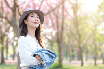 Young woman with smilling in cherry blossom garden in Spring day morning