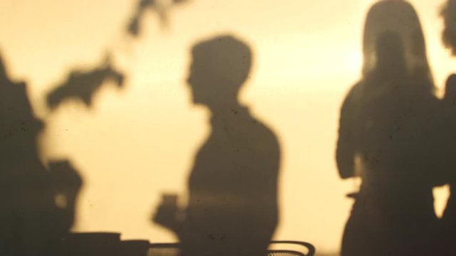 Shadows of four adults socialising on a Brooklyn rooftop