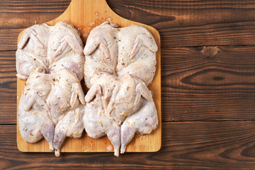 Raw quails in spices on a wooden background. Close-up.