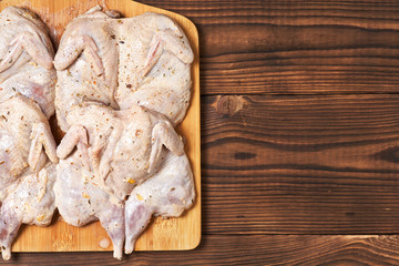 Raw quails in spices on a wooden background. Close-up.