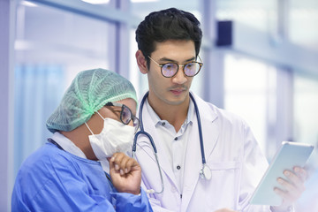 Asian surgeon team using digital tablet at work in operating room