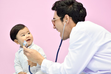 Asian pediatrician examining a baby with a stethoscope in a hospital
