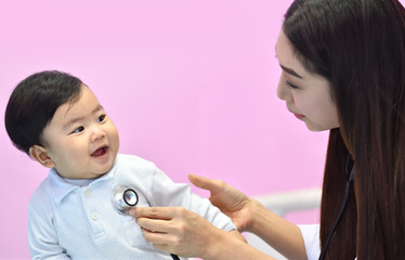 Fototapeta premium Asian pediatrician examining a baby with a stethoscope in a hospital