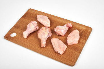 Raw chicken wings on a cutting board isolated on white background.