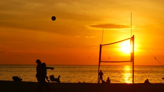 Slow Motion Video silhouette group of  person playing volleyball on the beach at sunset time with sunlight in sport and lifestyle concept.