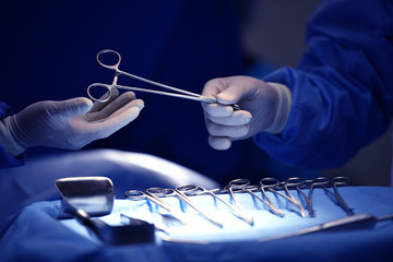 Surgeon hand picking up an instrument from tray of surgical instruments